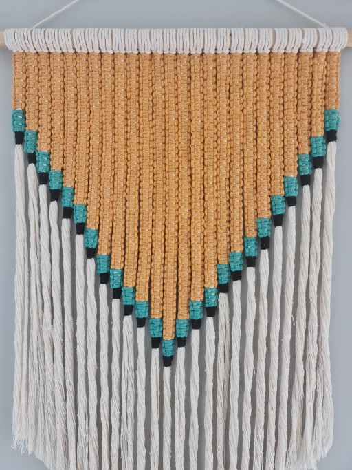 Feito à mão, com design geométrico e contas em tons de mostarda, azul-turquesa e preto sobre franjas brancas, feitos com materiais resistentes e prontos para pendurar.